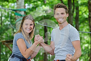 young man and woman arm wrestling during adventure course