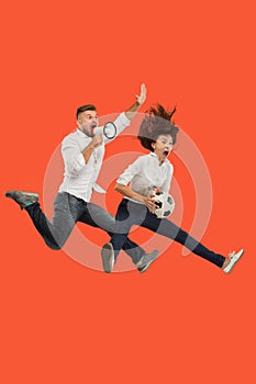 The young man and woman as soccer football players kicking the ball at studio