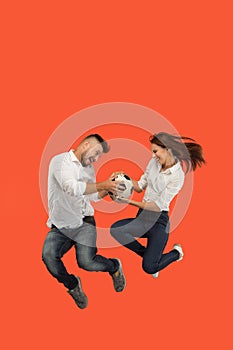 The young man and woman as soccer football players kicking the ball at studio