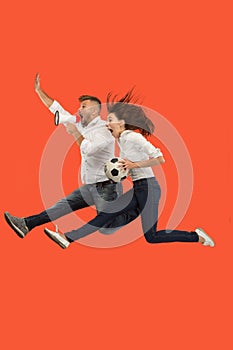 The young man and woman as soccer football players kicking the ball at studio