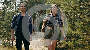 Young man and woman in casual comfortable clothes walking in forest on warm day, enjoying fresh air and nature