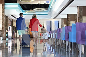 Young man, woman and child with suitcase go to hotel lobby