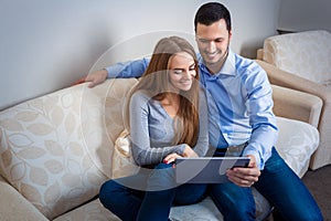 Young man and woman on the couch with electronic tablet