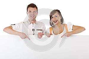 Young man and woman in dirndl pointing at ad space
