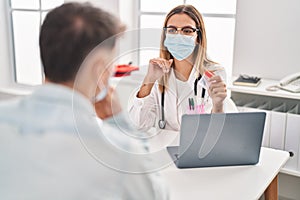 Young man and woman doctor and patient wearing medical mask holding urine test tube at clinic