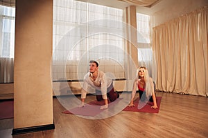 Young man and woman doing yoga exercise cat