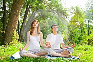 Young man and woman doing yoga in garden