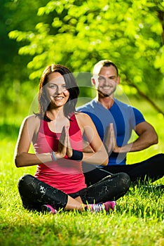 Young man and woman doing yoga in the sunny summer