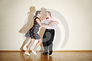 Young man and woman in dress dance at boogie-woogie party.