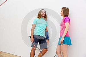 Young man and woman dressed in sportive wear talking before squash match