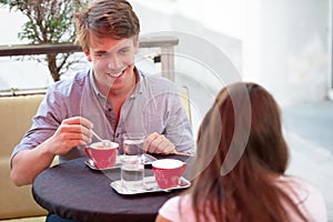 Young man and woman drinking coffee outdoor and having a chat on