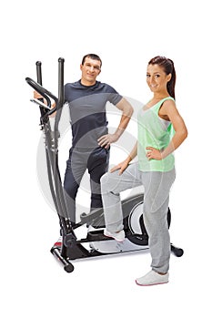 Young man and woman with elliptical cross trainer.