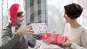 Young man and woman exchanged Christmas gifts. Couple in love exchanges gifts and spends Christmas holidays together