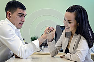 Young man and woman fight on his hands at the Desk in the office for a place Boss, head. The battle of the sexes, young couple hav