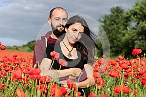 Young man and woman having date in the field of poppies