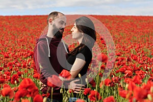 Young man and woman having date in the field of poppies