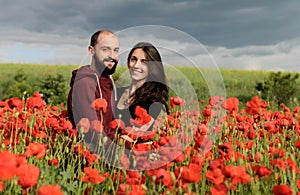 Young man and woman having date in the field of poppies