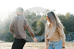 Young man and woman are having fun and dancing on the beach. Sunny cool weather outside