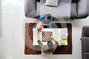 Young Man And Woman Having Fun With Dog While Playing Chess