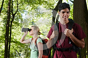 Young man and woman hiking with binoculars