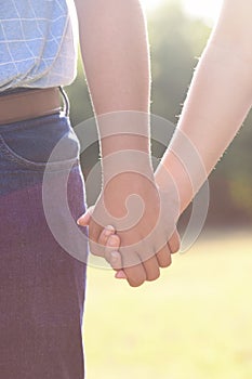 Young Man and Woman Holding Hands Outside in the Sun