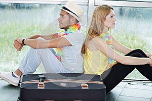 young man and woman looking through window at airport