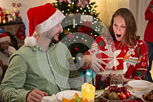 A young man and woman open gift boxes at a Christmas party at home during the holidays