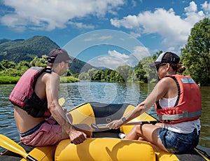 Young man and woman paddling in inflatable raft on Slovak mountain river Orava