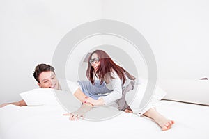 Young man and woman in pillow fight smiling