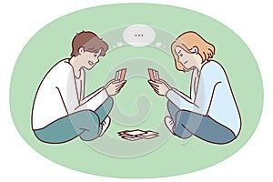 Young man and woman play cards sitting on floor and think what next move to make