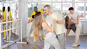 Young man and woman practicing waltz dance in pair in training hall