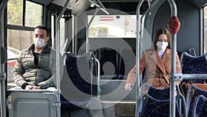 Young man and woman with protective mask traveling in the public transport by bus