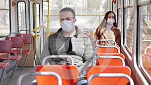 Young man and woman with protective mask traveling in the public transport by bus