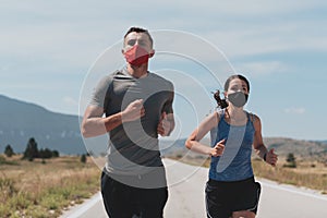 Young man and woman in protective masks running and doing exercises outdoors in the morning. Sport, Active life Jogging