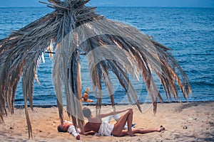 Young man and woman relax on sand by a sea on summer beach.