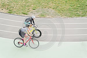 Young man and woman are riding on bike track in athletic wear on the stadium in Kiev, Ukraine