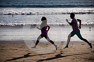 Young man and woman running jogging along the sea. Couple running on beach.