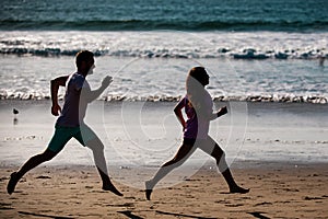 Young man and woman running jogging along the sea. Couple running on beach.