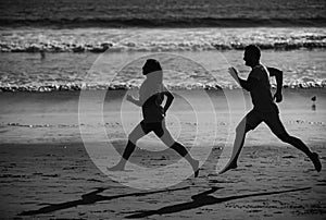 Young man and woman running jogging along the sea. Couple running on beach.