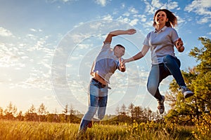 Young man and woman running and jumping. Couple having fun in spring field at sunset.