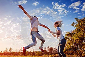 Young man and woman running and jumping. Couple having fun in spring field at sunset. Guys enjoying life.