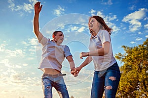 Young man and woman running and jumping. Couple having fun in spring field at sunset. Guys laughing