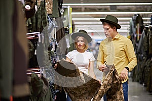 Young man and woman in search of equipment for hunting in store