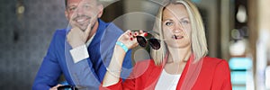 Young man and woman sit at bar with sunglasses in their hands