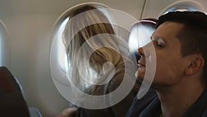 Young man and woman sitting near the window and looking on the view outside. Couple traveling by plane together.