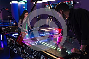 Young man and woman smiling while playing air hockey