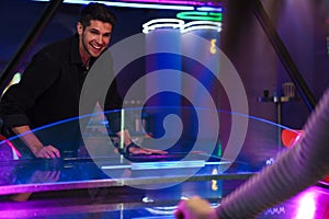 Young man and woman smiling while playing air hockey