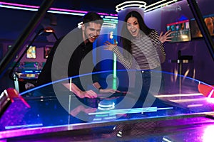 Young man and woman smiling while playing air hockey