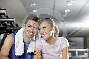 Young man and woman smiling and sitting together at the gym