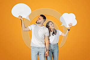 A young man and woman smilingly hold up blank speech bubbles, symbolizing communication or dialogue photo